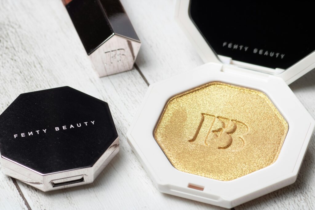 Close-up of Fenty Beauty highlighter with elegant packaging on a wooden surface.